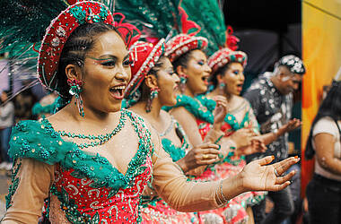Tänzerinnen beim Karneval in Oruro. Sie tragen grünrote Kostüme und rote Hüte mit einer grünen Feder